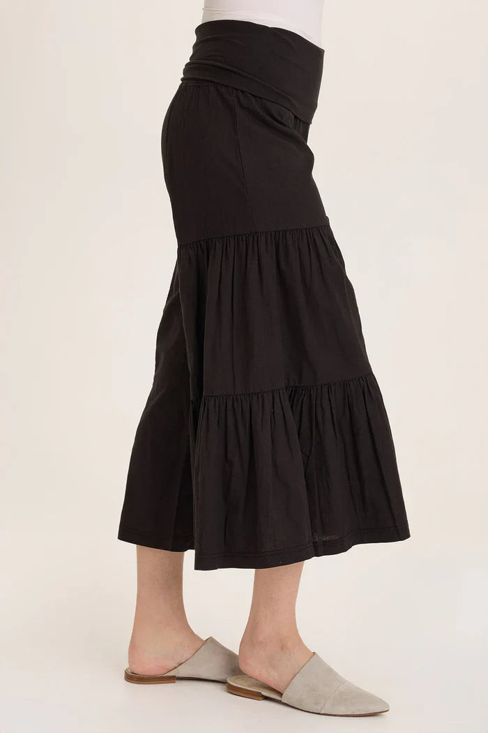 Side profile of black tiered wide-leg culottes paired with beige slippers