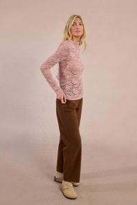 Full-length side view of blush lace long sleeve top styled with brown pants
