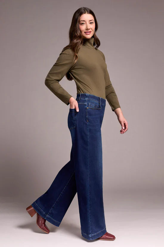 Side view of model in high-rise wide leg jeans paired with olive top and heeled boots