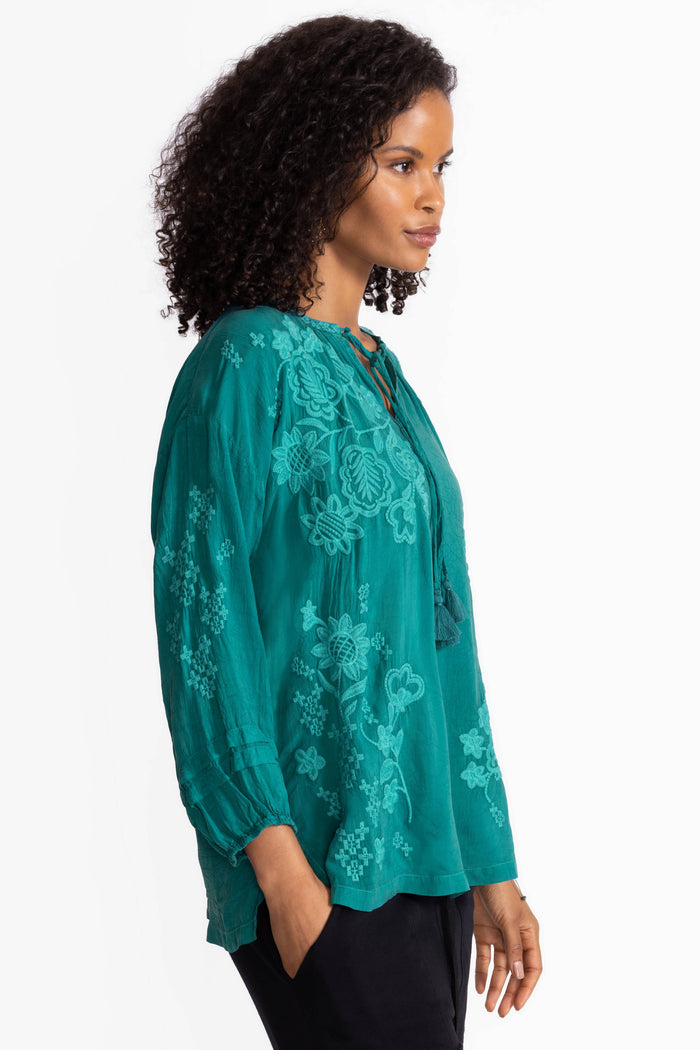 Side view of teal floral embroidered blouse with three-quarter sleeves