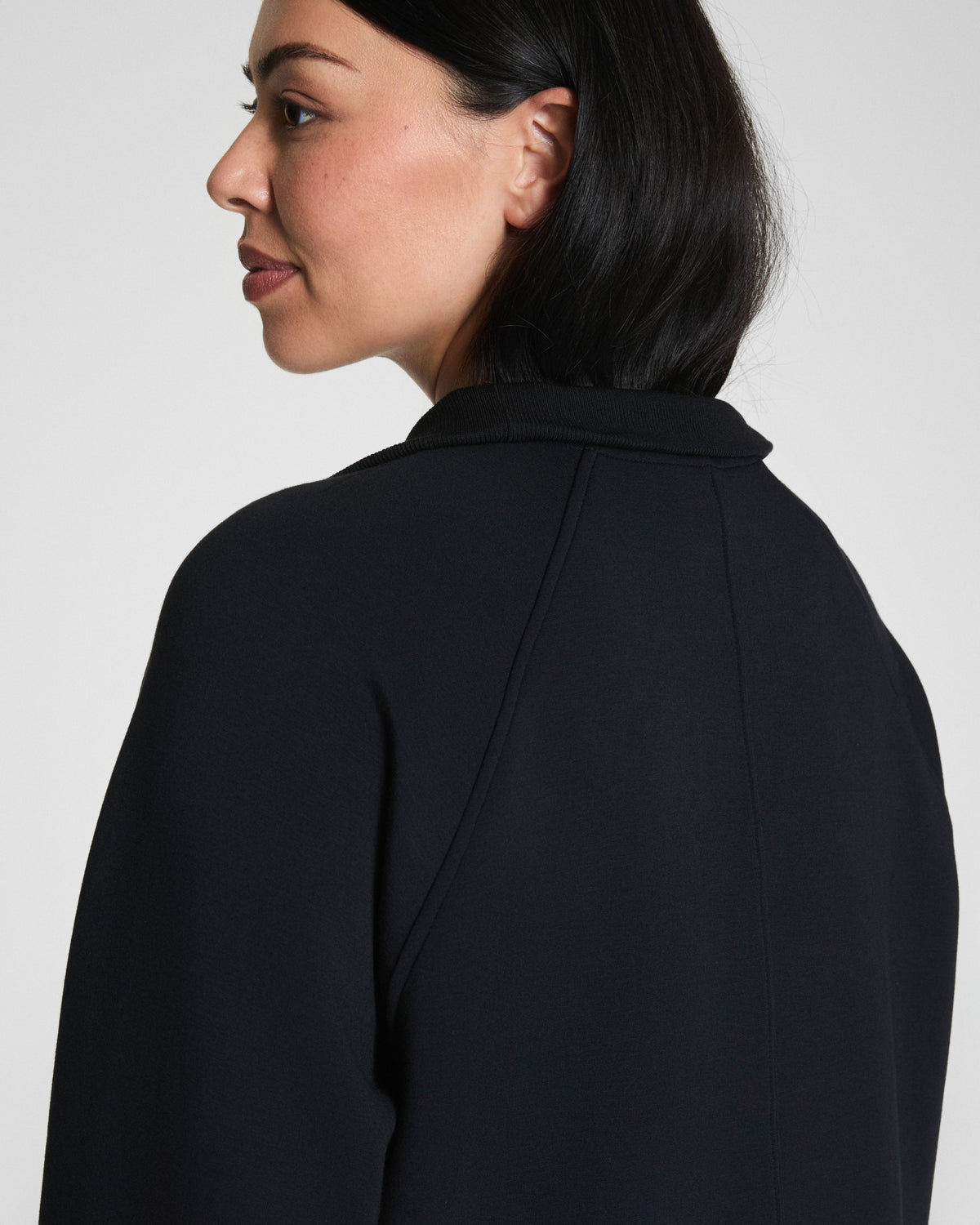 Close-up of woman wearing a black quarter-zip pullover, side profile view