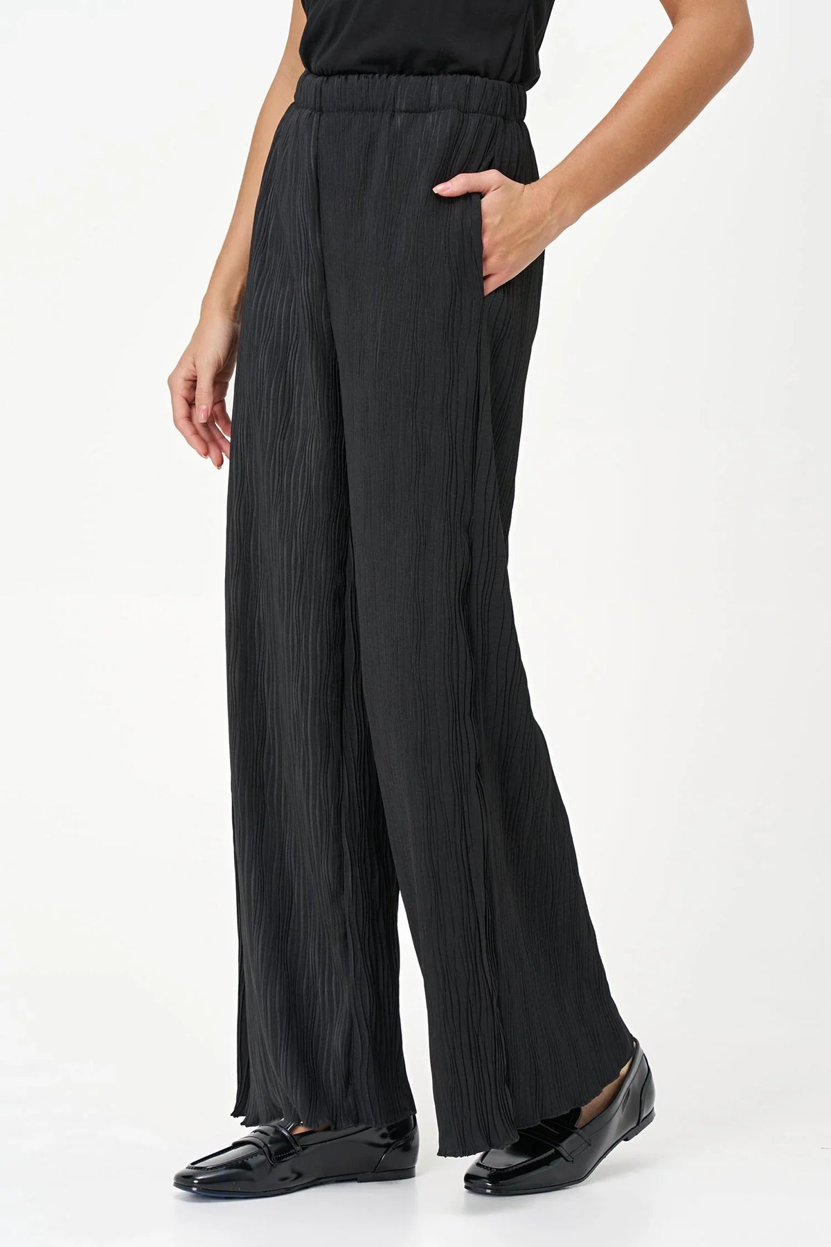 Side angle of black wave-textured wide-leg pants with hand in pocket