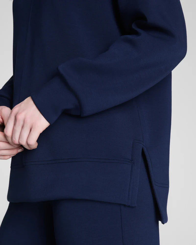 Close-up of side slit and hem detail on navy mock neck sweatshirt