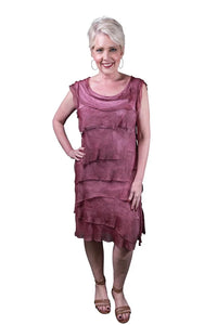 Woman wearing a sleeveless tiered mauve dress with layered textured details