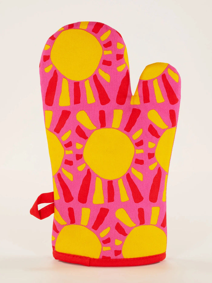 Brightly colored oven mitt with yellow sunburst design on a pink background, back side shown