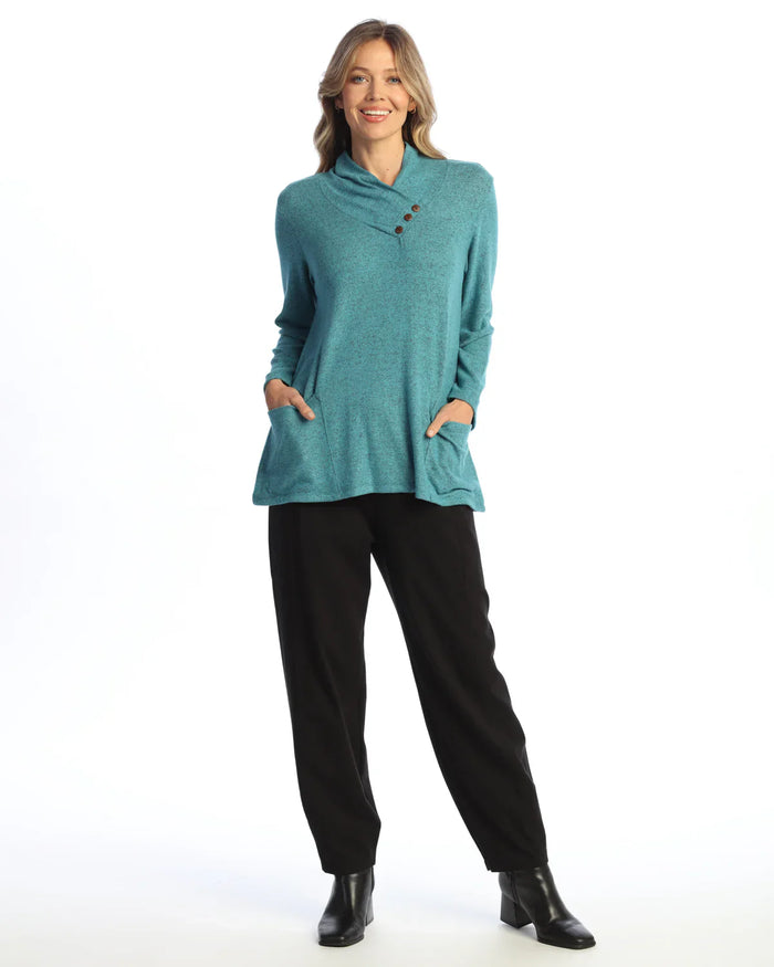 Woman wearing a teal asymmetrical knit tunic with buttons and pockets