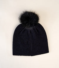 Top view of black beanie hat with large black faux fur pom pom