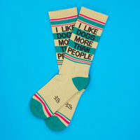 Two cream socks with colorful stripes and 'I Like Dogs More Than People' in bold letters