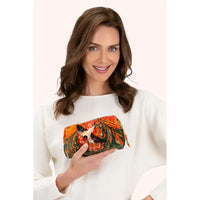 Woman holding a vibrant velvet bird-print makeup bag