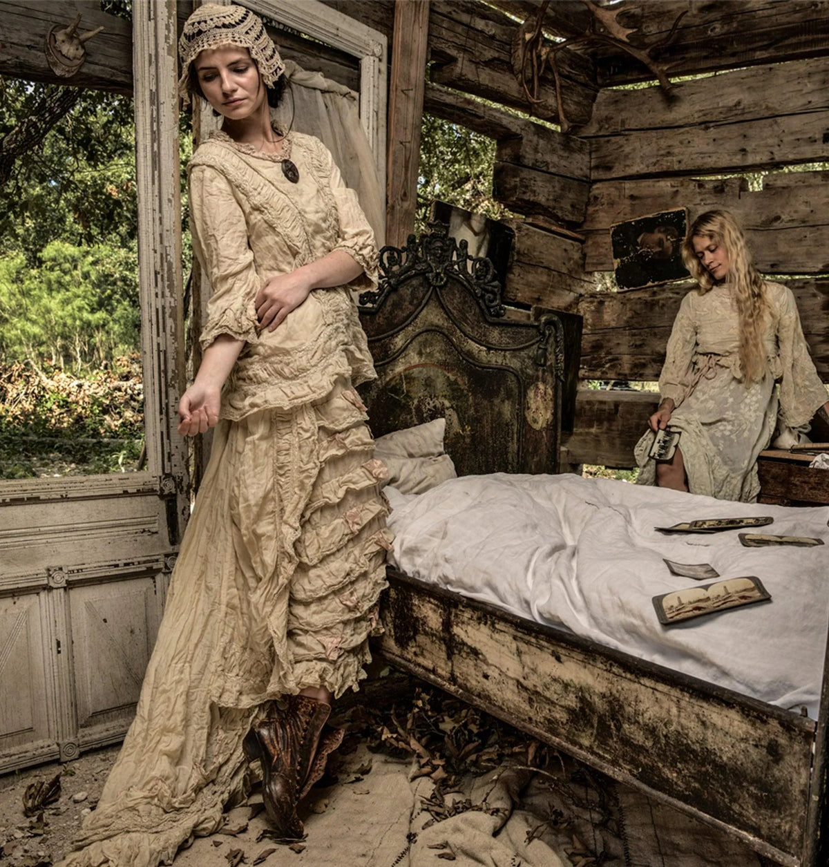Two women in romantic vintage dresses in a weathered, antique bedroom setting