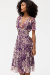 Side angle of a woman in a violet lace floral midi dress with intricate embroidery
