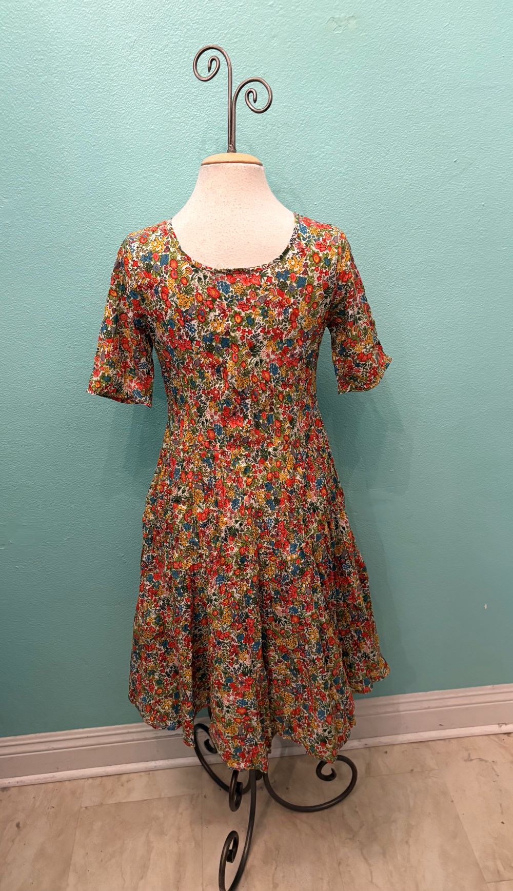 Front view of a whimsical floral dress with colorful meadow pattern on a mannequin
