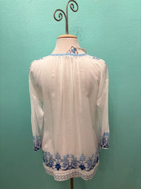 Back view of white boho blouse with blue floral embroidery and long sleeves