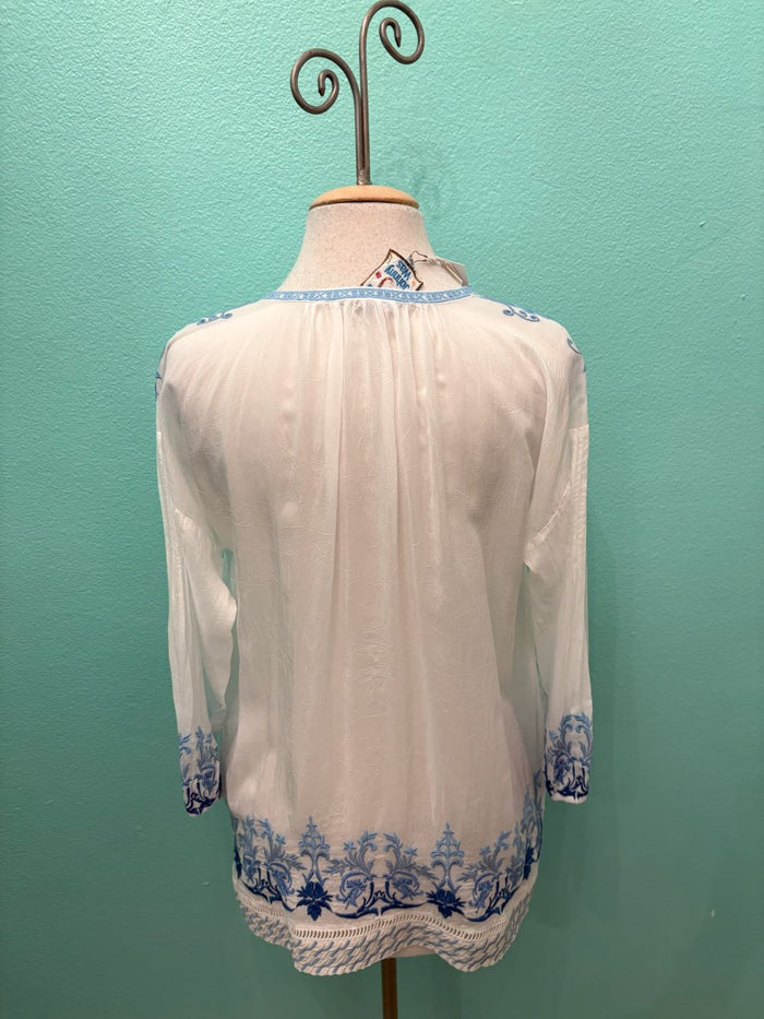 Back view of white boho blouse with blue floral embroidery and long sleeves