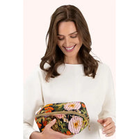 Woman smiling while holding velvet floral cosmetic bag