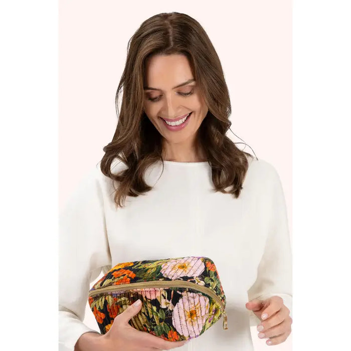 Woman smiling while holding velvet floral cosmetic bag