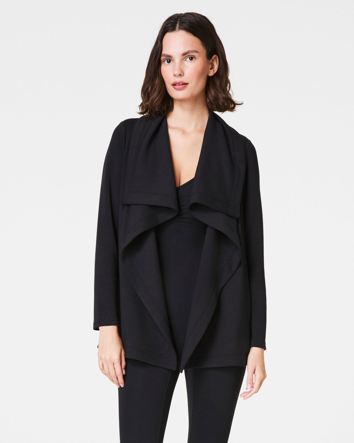 Woman wearing a black drape front cardigan over matching black outfit