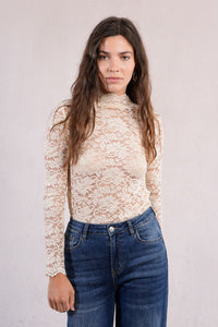 Front portrait of woman in an ivory lace mock neck top with jeans