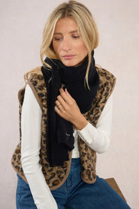 Woman wearing jet black scarf with bow embroidery, styled for winter