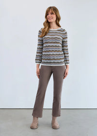 Full body view of woman wearing taupe straight-leg jeans and a wavy striped sweater