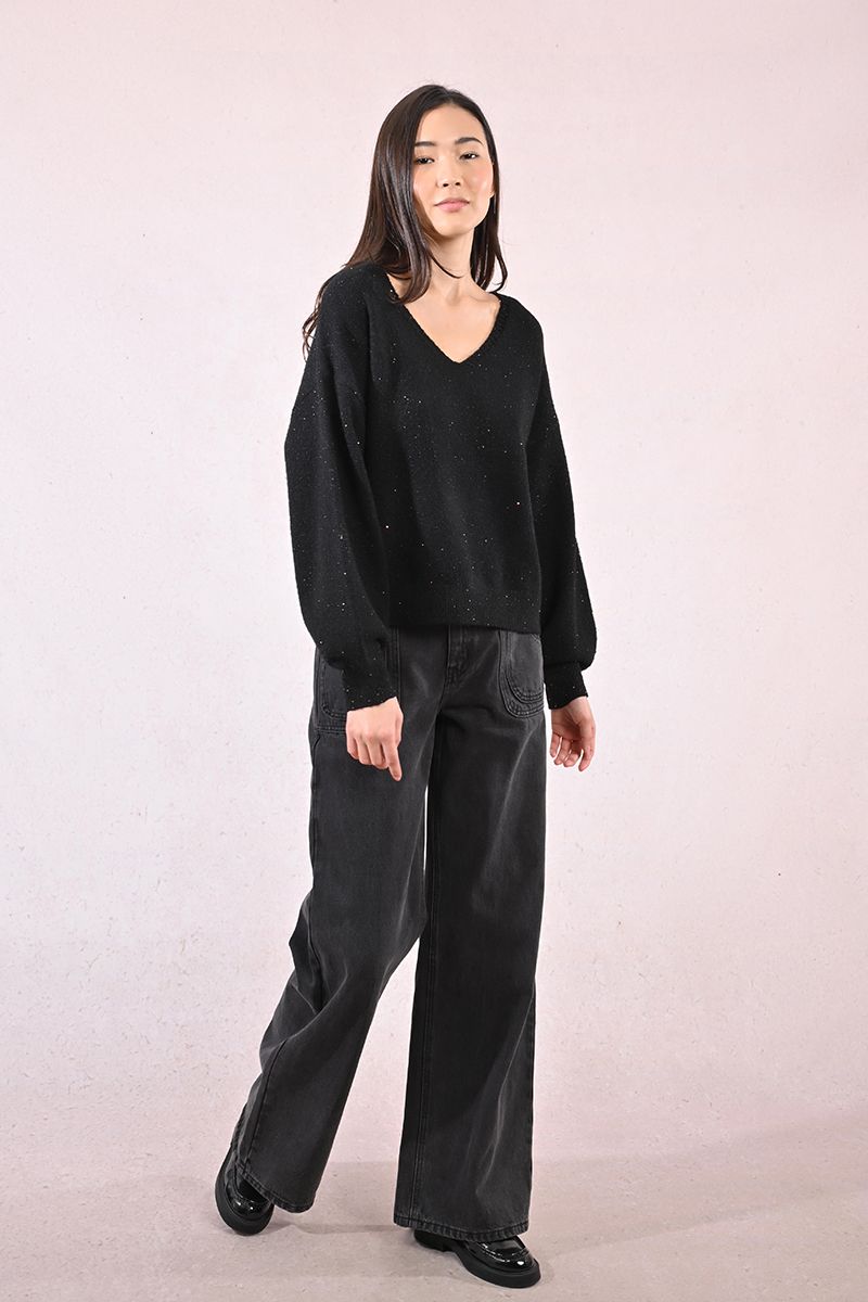 Full body shot of woman in black sparkly sweater and wide-leg black jeans
