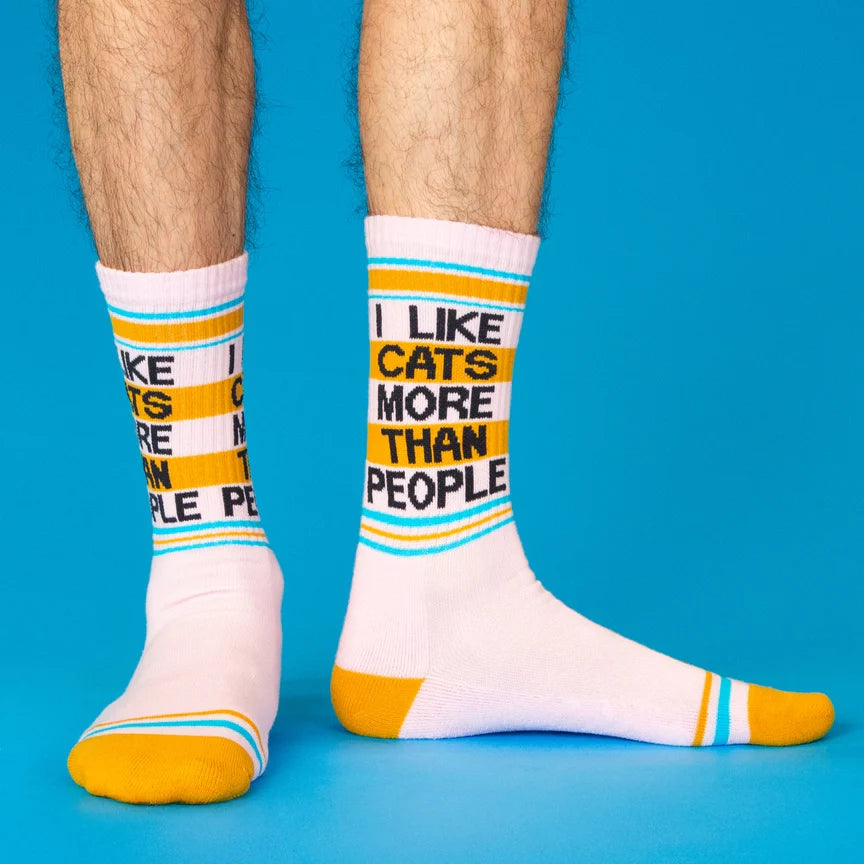 Person wearing pink socks with yellow and blue stripes, and text 'I like cats more than people'